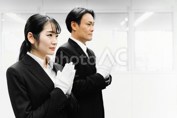 白手袋をつけて合掌するスーツ姿の男女 葬祭ディレクター,白手袋,礼服の写真素材