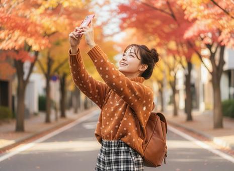 スマフォで紅葉を撮影する若い女性 スマフォで紅葉を撮影する若い女性の写真
