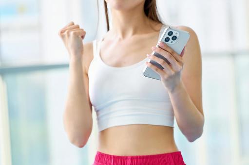 スマホを見てガッツポーズする女性の手 トレーニング,スマホ,ガッツポーズの写真素材
