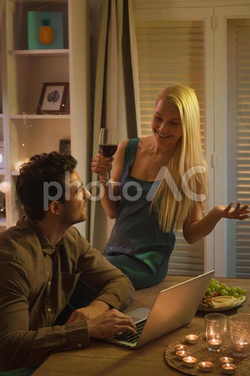 ワイングラスを持ってパソコンの男性と話す女性 男女,カップル,ワインの写真素材