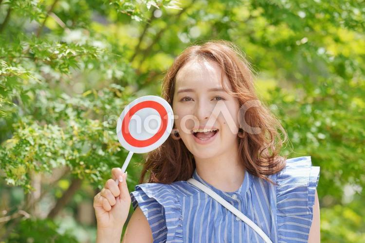 木の前でマルの札を出す女性 女子旅,女性,日本人の写真素材