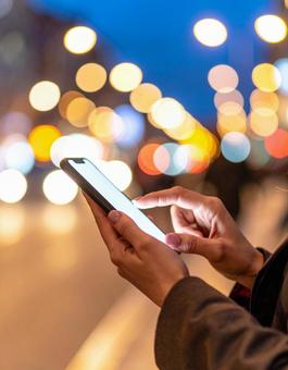 スマホを操作する女性の手と柔らかな背景 スマホを操作する女性の手と柔らかな背景の写真