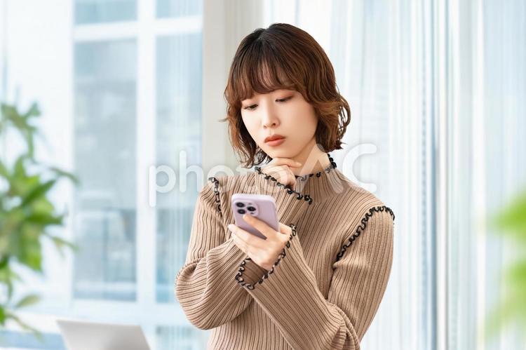 スマホを見て考える女性・ビジネスウーマン 女性,困る,人物の写真素材