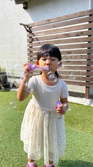 庭でシャボン玉をする女の子 庭でシャボン玉をする女の子の写真