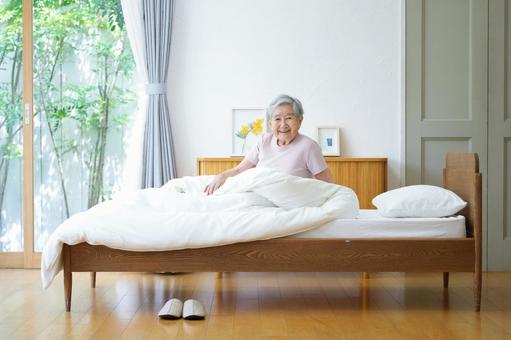 ベッドで微笑みカメラ目線の高齢女性 女性,ベッド,座るの写真素材