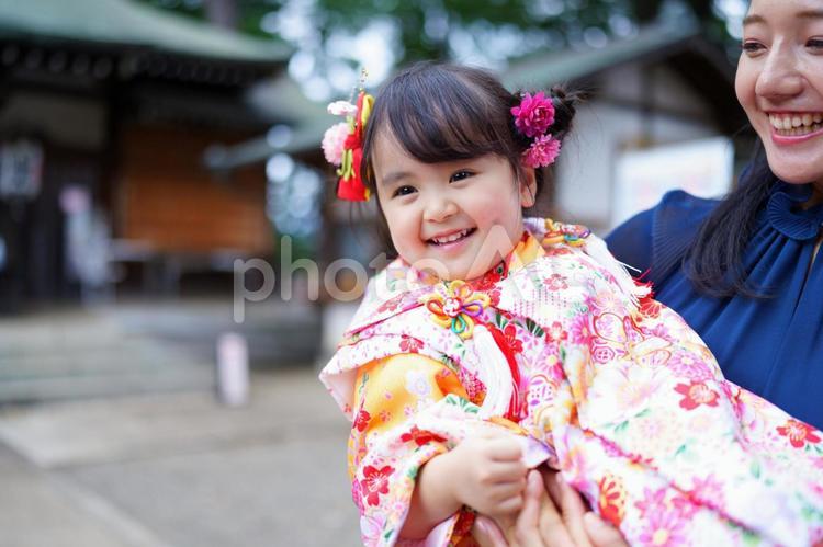 母親に抱かれて笑顔を見せる着物姿の女の子 七五三,お参り,七五三参りの写真素材