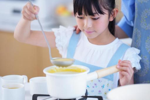 おたまでスープをすくうエプロン姿の女の子の写真