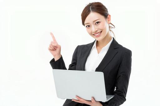 パソコンを持ち指をさす女性-4の写真