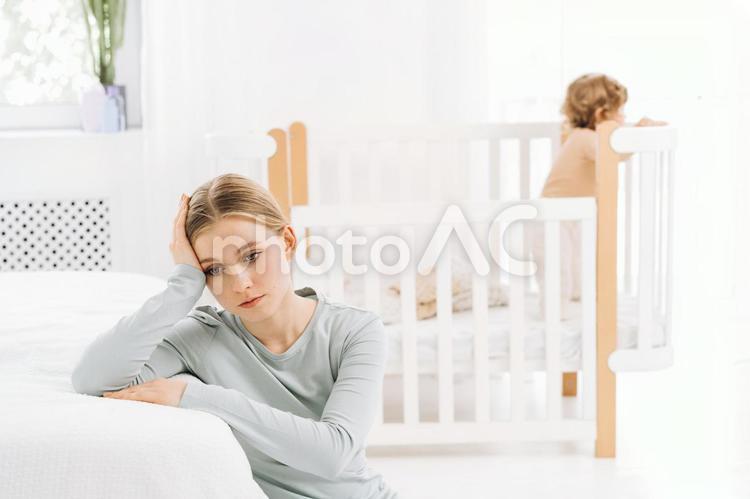 頭を押さえ辛そうな真顔の女性 育児疲れ,疲れた,座るの写真素材