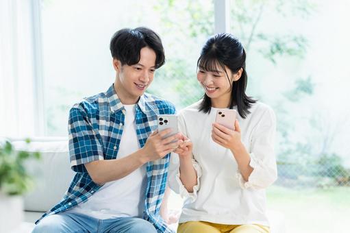 リビングでスマホを見るカップル スマホ,笑顔,カップルの写真素材