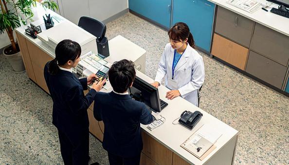病院の会計窓口で会計をする男性患者 病院の会計窓口で会計をする男性患者の写真