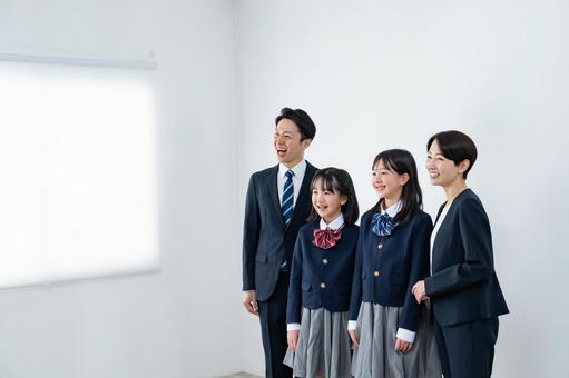スーツを着た男女と制服を着た女の子二人 スーツを着た男女と制服を着た女の子二人 入学式,父母,母親の写真素材
