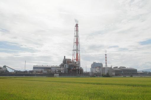 田畑の中の工場、富山県高岡市 煙突,田んぼ,越中パルプ工業の写真素材