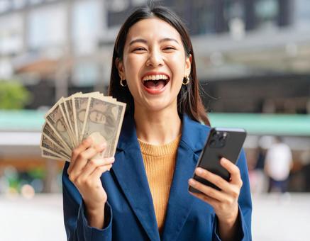お金を手にして喜ぶ女性 お金を手にして喜ぶ女性の写真