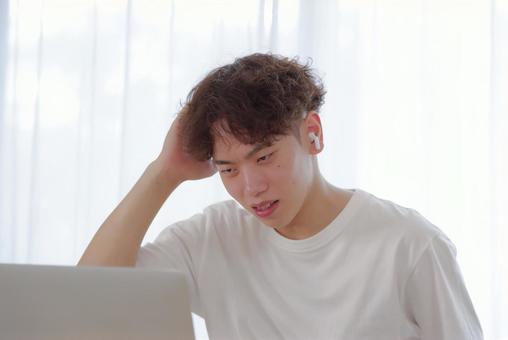 リビングでパソコン作業をする若い男性 リビングでパソコン作業をする若い男性 考える,悩む,真剣の写真素材