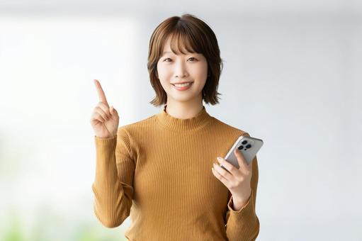 スマホを持って案内をする笑顔の女性 スマホを持って案内をする笑顔の女性 女性,スマホ,笑顔の写真素材
