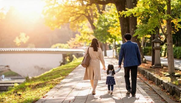 公園を歩く日本人の３人家族の写真