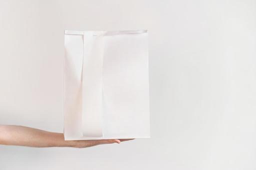 白い紙袋を乗せた手 配達,フードデリバリー,テイクアウトの写真素材