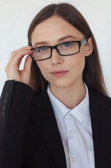 メガネフレームを持ちカメラ目線の女性の写真