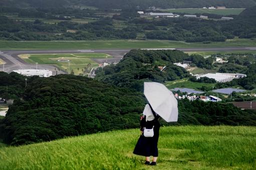 素材>高台から空港を見下ろす旅行中の女性 素材>高台から空港を見下ろす旅行中の女性 女性,山登り,滑走路の写真素材