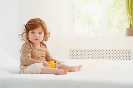 窓際の明るい場所で玩具を持ち座る子供 窓際の明るい場所で玩具を持ち座る子供 赤ちゃん,かわいい,お座りの写真素材