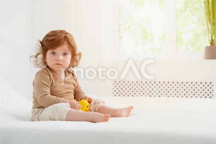窓際の明るい場所で玩具を持ち座る子供 赤ちゃん,かわいい,お座りの写真素材
