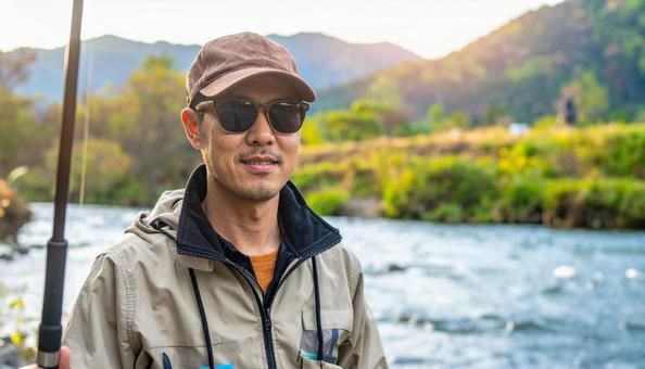 サングラスをして渓流釣りをする男性 サングラスをして渓流釣りをする男性の写真