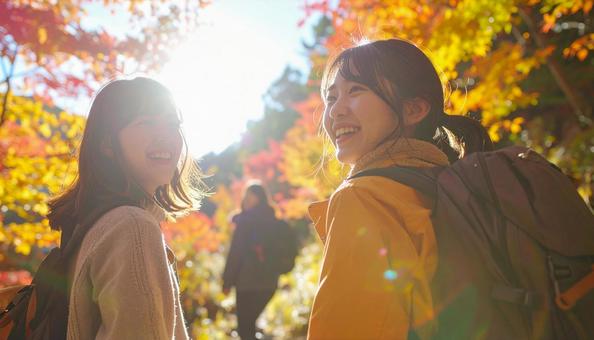 紅葉の中を笑顔でハイキングする女性たち 紅葉の中を笑顔でハイキングする女性たちの写真