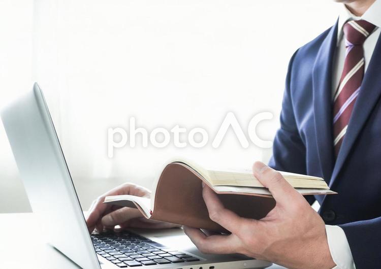 ノートパソコンと手帳で作業するビジネスマン ノートパソコン,ノートpc,パソコンの写真素材