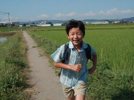 田舎の道を走る男児 田舎の道を走る男児の写真