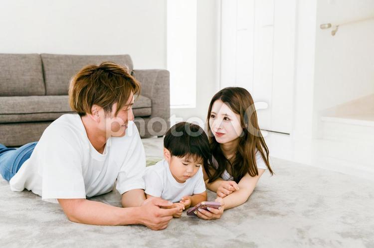 リビングでスマホを見る笑顔の日本人家族 知育,スマホ,英才教育の写真素材