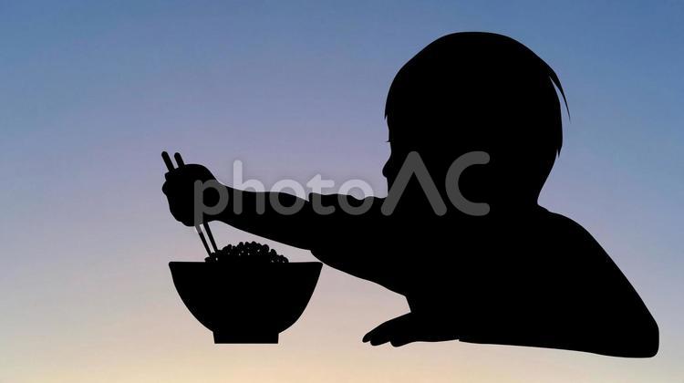 ご飯を食べる男児シルエット_薄暗い背景 子供,ご飯,男の子の写真素材