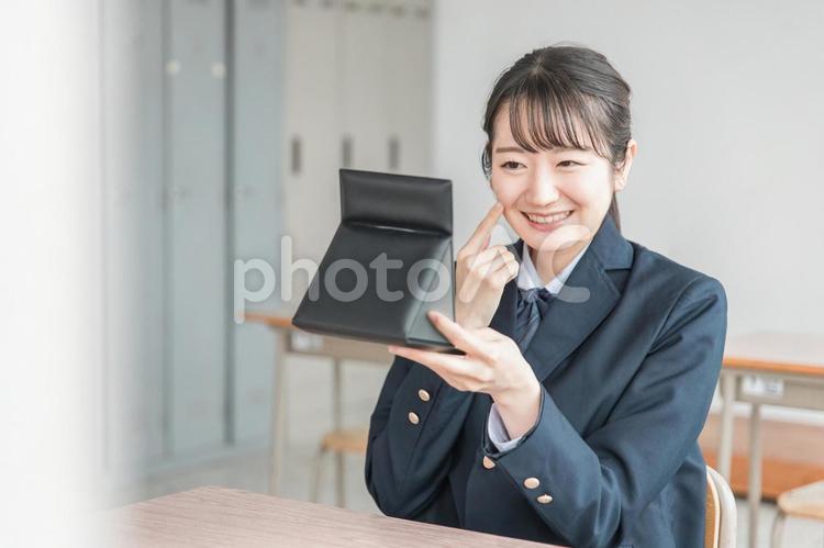 学校の教室で鏡を見る笑顔の女子高生 女子高生,ニキビ,肌荒れの写真素材