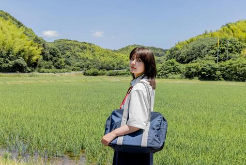 青空と田園を背景にたたずむ女子高校生 女子高校生,高校生,学生の写真素材