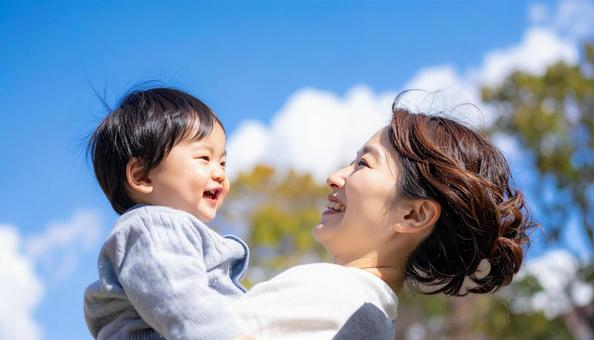 青空の下、子供を抱っこする母親 青空の下、子供を抱っこする母親の写真