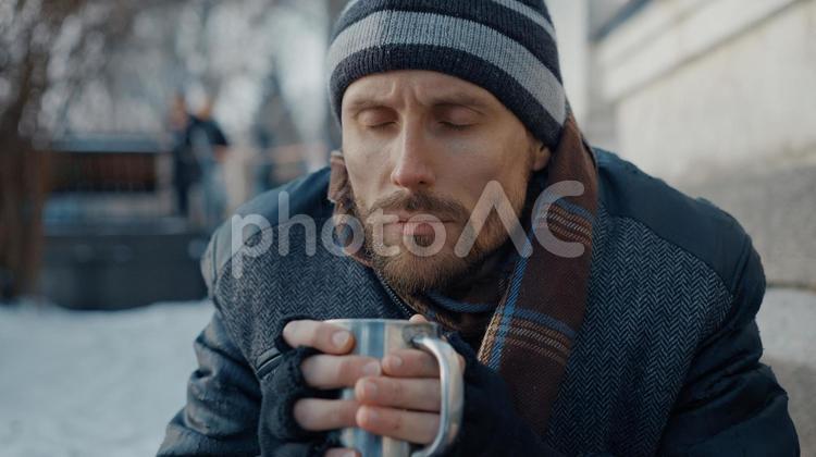 目を瞑ってカップを持つ男性 男性,ニット帽,人物の写真素材