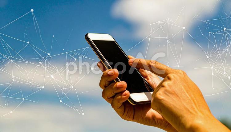 スマートフォンを操作する手　青空背景 スマートフォン,メール,ラインの写真素材