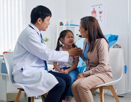 小児科で幼児を診察する医者 小児科で幼児を診察する医者の写真