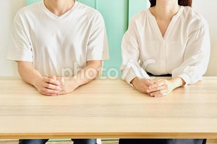机に横並びで座る男性と女性 夫婦,カップル,2人の写真素材