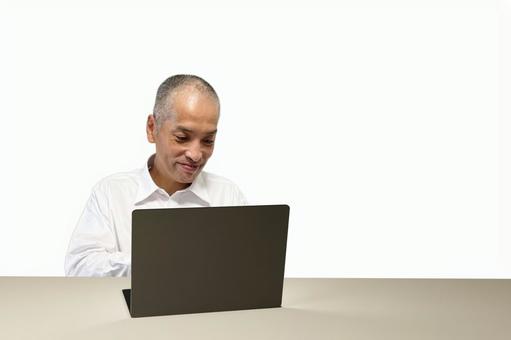ノートパソコンで作業する笑顔の中年男性 ノートパソコンで作業する笑顔の中年男性 男性,パソコン,笑顔の写真素材