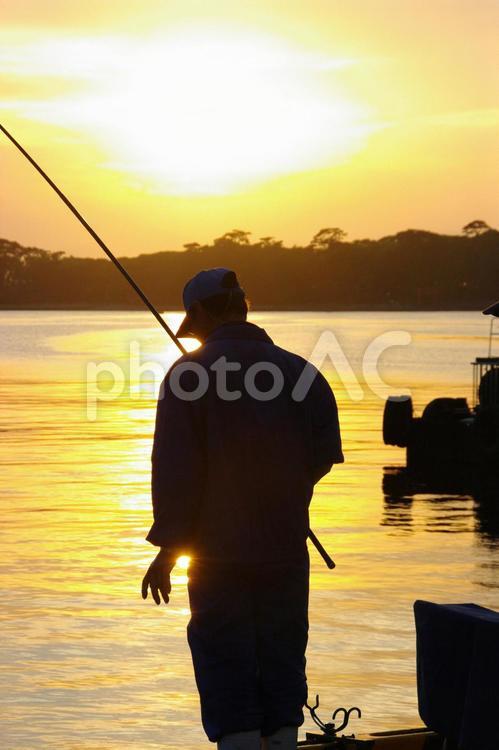 夕景の中で釣りを楽しむ 釣り人,魚を釣る人,夕焼けの海の写真素材