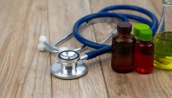 医学イメージ　聴診器と赤と黄色の試薬の写真