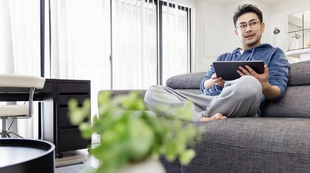 ソファーでタブレットを使う男性 ソファーでタブレットを使う男性 男性,人物,日本人の写真素材