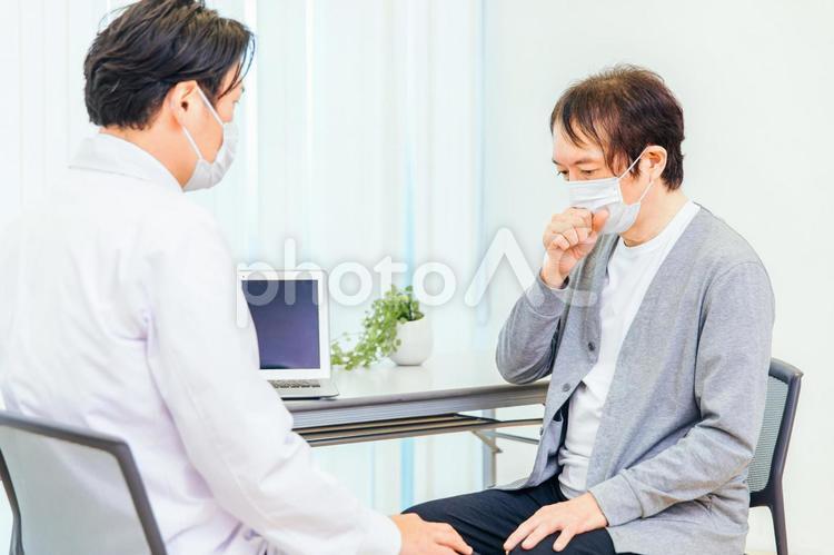 パソコンで診察するマスク姿の男性医師（せき） 咳,ぜんそく,喘息の写真素材