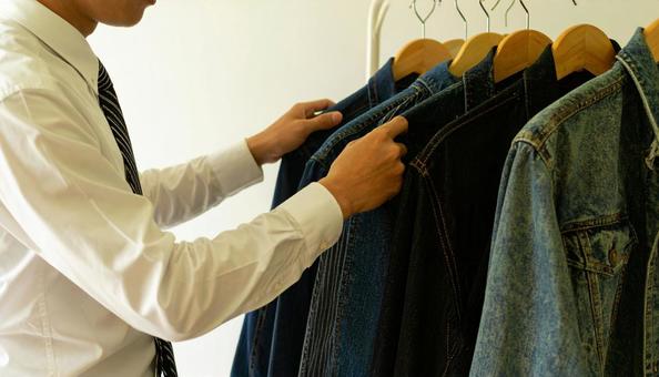 ハンガーにかかる私服を取るビジネスマンの写真