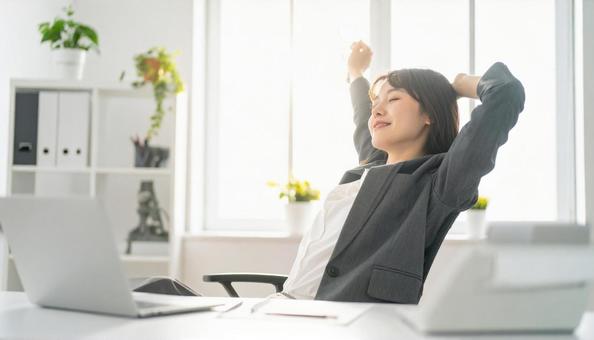 仕事が終わり達成感で背伸びをする社員 仕事が終わり達成感で背伸びをする社員の写真