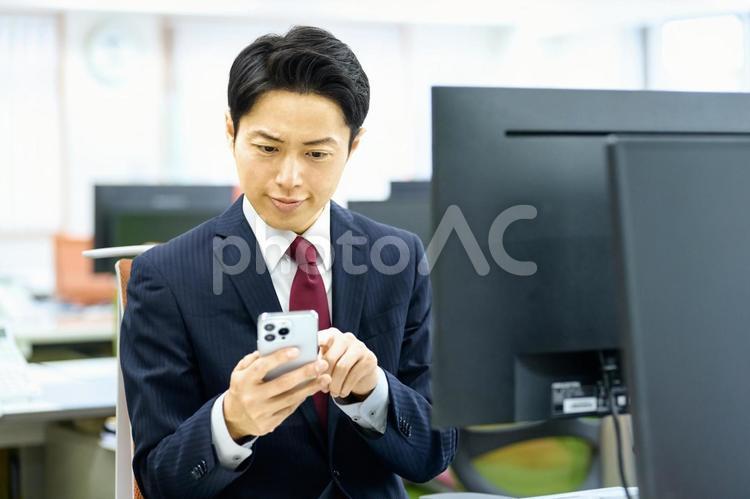 スマホを使うビジネスマン　会社員　電話 ビジネスマン,スマホ,見るの写真素材