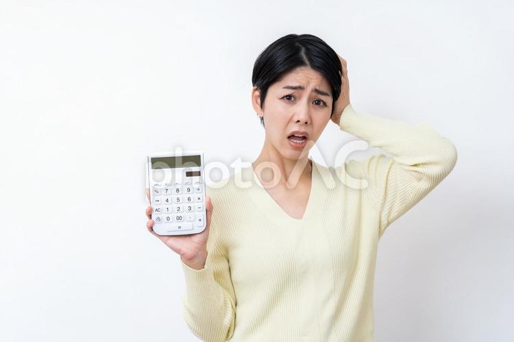 頭を抱える電卓を持った女性。 主婦,電卓,家計の写真素材
