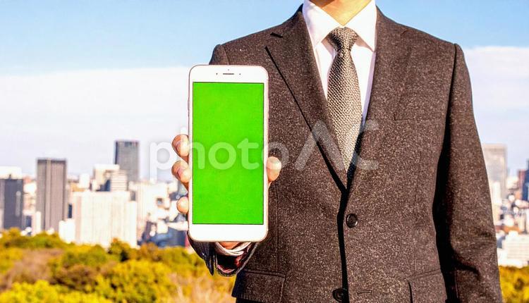 携帯画面を見せるビジネスマン スマートフォン,都市,高層ビルの写真素材