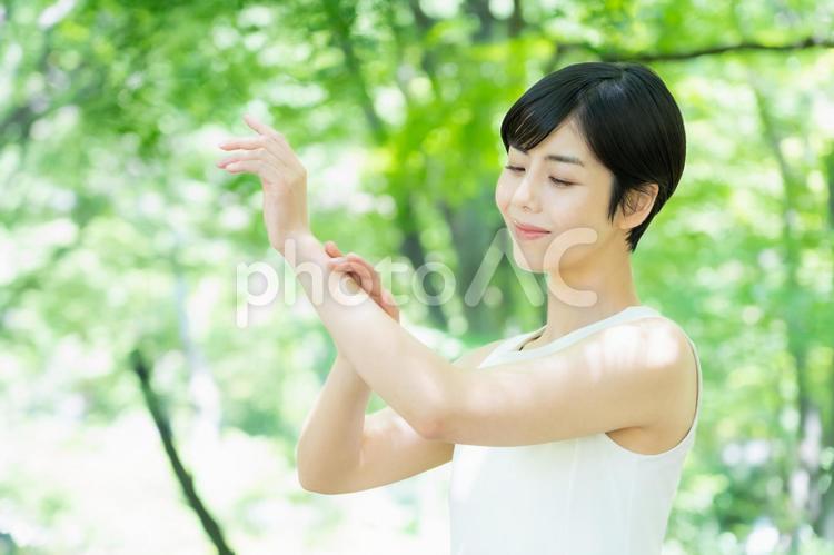 緑の中でスキンケアをする若い女性 スキンケア,ビューティー,女性の写真素材